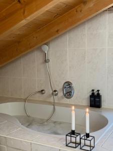 a bath tub with two candles in a bathroom at Soleils Living I See & Berge I Starnberger See in Berg am Starnberger See