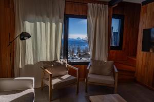 a living room with two chairs and a large window at Vandor in San Martín de los Andes