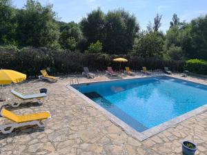 a swimming pool with chairs and umbrellas in a yard at Auberge de l'Escargot d'Or in Dieulefit