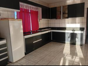 eine Küche mit schwarzen Schränken und einem roten Vorhang in der Unterkunft Casa ampla e aconchegante in Foz do Iguaçu + 19 Fotos