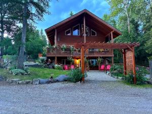 a log cabin with a deck and red chairs at Timber Wolf Resort in Hungry Horse