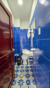 a blue tiled bathroom with a toilet and a sink at Hotel Sueños Libres Necoclí in Necoclí