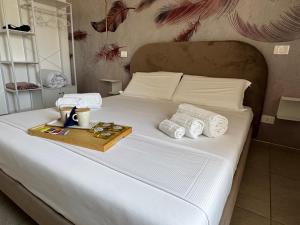a white bed with a tray of towels and a tray at Serèsia Rooms Siracusa Centro in Syracuse
