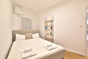 una piccola camera da letto con un grande letto con lenzuola bianche di Luxe on the BEACH By LIME a Haifa