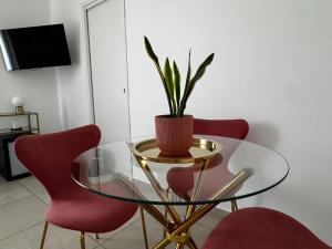 a glass table with two red chairs and a plant on it at Serèsia Rooms Siracusa Centro in Syracuse