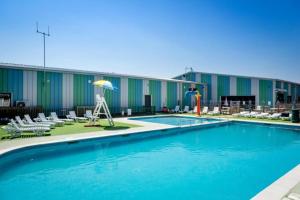 a pool with chairs and an umbrella in front of a building at Seawick Caravan 922 in Clacton-on-Sea