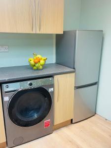 een keuken met een wasmachine en een koelkast bij Newly refurbished spacious studio flat in Wimbledon in Raynes Park
