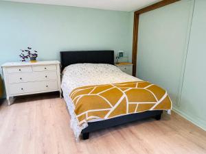 een slaapkamer met een bed en een witte dressoir bij Newly refurbished spacious studio flat in Wimbledon in Raynes Park