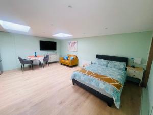 een slaapkamer met een bed, een tafel en een televisie bij Newly refurbished spacious studio flat in Wimbledon in Raynes Park