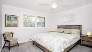 a white bedroom with a bed and a chair at Oceanique in Old Bar +14 photos