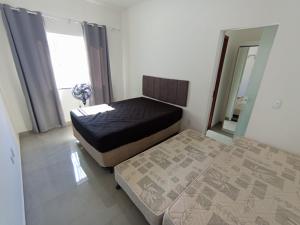 a small bedroom with two beds and a mirror at Casa Rua da Lagoa in Araruama