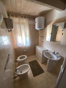 ein Badezimmer mit zwei Waschbecken und einer Toilette und einem Spiegel in der Unterkunft Appartamento Carnovale WiFi Piscina divertimento sul mare di Pizzo in Fondaco Vecchio