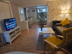 Una sala de estar con un sofá y un televisor. en L ' Arlequin Suite et logement, en Vaudreuil-Dorion