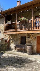 a building with a bench and a balcony with flowers at The Walnut tree in San Miguel de Luena