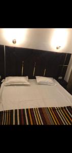 Una cama con sábanas blancas y almohadas en una habitación. en Hotel Gurujee residence, en Amritsar