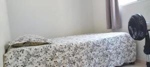 a bedroom with a bed with a flowered blanket and a window at Condomínio Citta COP30 in Marituba