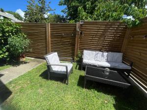 zwei Stühle und eine Bank in einem Hinterhof in der Unterkunft Cocon douillet entre Mer et Montagne in Basse-Terre