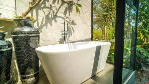 a white bath tub sitting next to a large vase at Zamaya Bangalôs in Sao Jorge