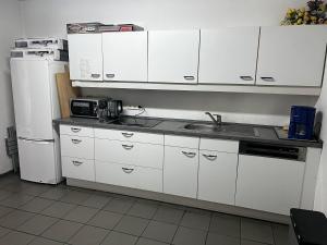 a kitchen with white cabinets and a sink and a refrigerator at TL Gastzimmer in Frankfurt/Main