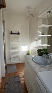 a white bathroom with a sink and a mirror at La Vigie - Maison en bord de mer in Lion-sur-Mer