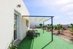 a patio with green grass and a white umbrella at EyA House in Padul