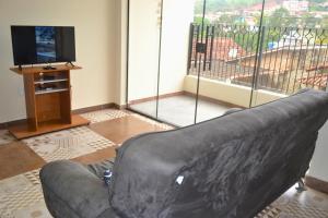 a black leather couch in a living room with a television at Seu lugar na Mantiqueira é aqui! Seja bem-vindo! in Itanhandu