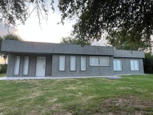 a gray house with white windows in a yard at Mía Casa de Campo in Unquillo