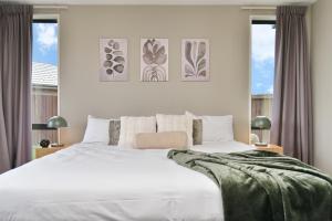 um quarto com uma grande cama branca e duas janelas em Spacious Family & Group Retreat - Wigram Residence em Christchurch