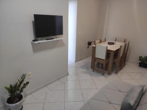 sala de estar con mesa y TV en la pared en Apartamento com suíte no bairro de Santa Monica, en Uberlândia