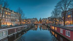 a river in a city with houses and buildings at Spacious Room with private king bathroom in Amsterdam