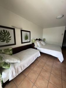 two beds in a room with a tiled floor at Karibbean Resort in Sainte-Luce