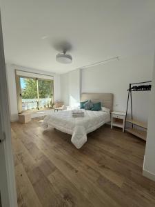 a white bedroom with a large bed and wooden floors at Alojamientos, Rafael muñoz in Alcaudete