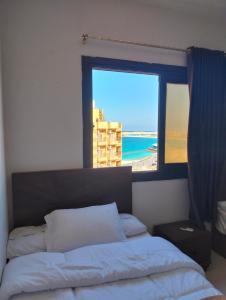 a bedroom with a bed and a window with a view of the beach at Luxury units for rent on the sea Marsa Matrouh in Marsa Matruh