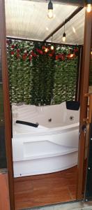 een wit bad voor een raam met rode bloemen bij La cabaña de Ciela Glamping con jacuzzi in Latacunga +12 foto's