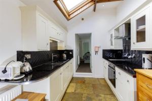 eine Küche mit weißen Schränken und schwarzen Arbeitsplatten in der Unterkunft Old Brewery Cottage - Elleanbeich - Isle of Seil 