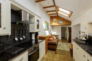 eine Küche mit Herd Top-Backofen neben einem Wohnzimmer in der Unterkunft Old Brewery Cottage - Elleanbeich - Isle of Seil 