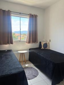 a bedroom with a bed and a window and a table at Apartamento próximo ao inhotim in Brumadinho