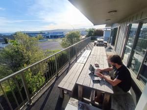 a man sitting on a picnic table with a laptop at Adventure Taupō Hostel in Taupo +12 photos