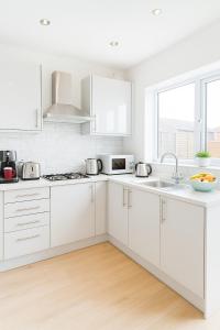 une cuisine blanche avec des armoires blanches et un évier dans l'établissement Stylish Platt bridge contractor Stays, à Abram