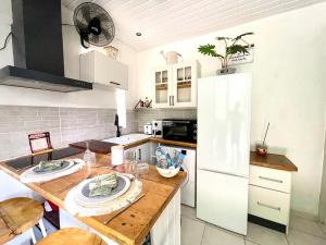 a kitchen with a wooden table and a white refrigerator at La Pierre des Ducs in Matoury