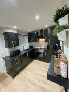eine Küche mit schwarzen Schränken und einer Arbeitsplatte in der Unterkunft Kingston Park House - Airport - Red Bulls Rugby in Kenton