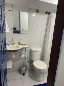 a white bathroom with a toilet and a sink at Suites a 5min da Broadway in Aracati