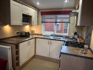 a small kitchen with white cabinets and a sink at Glen-coo in Auchterarder