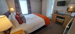 a hotel room with a bed and a desk and a television at Derrybeg Bed and Breakfast in Pitlochry