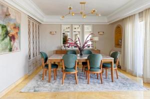 a dining room with a wooden table and green chairs at Zamalek Nile View in Cairo