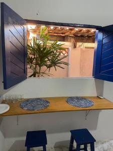 a counter with two blue stools and a window at Suites a 5min da Broadway in Aracati
