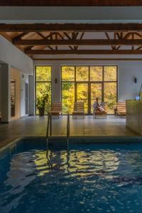 a person sitting on a bench next to a swimming pool at Lisine Lepo Mesto Guesthouse & Spa in Strmosten