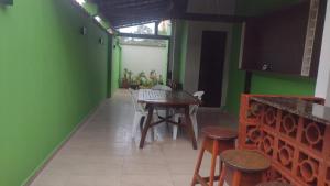 a dining room with green walls and a table and stools at Quarto para cop30 em casa de família in Belém