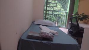 a bed with a blue blanket and a window with at Quarto para cop30 em casa de família in Belém