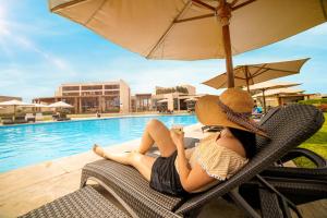 a woman sitting in a chair next to a swimming pool at Casa Andina Standard Chincha in Chincha Alta